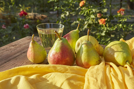 梨和苹果酒在玻璃杯中。熟鲜梨, 木桌上, 自然背景
