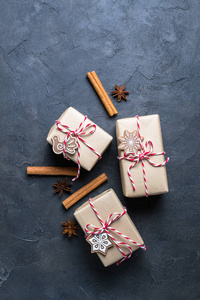 圣诞礼物或礼物盒包装在牛皮纸与装饰在黑暗的背景。礼物装饰与圣诞节饼干顶部视图与复制空间