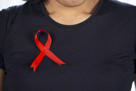 关闭未知的女人穿着黑色的衣服与红色丝带。世界艾滋病日概念