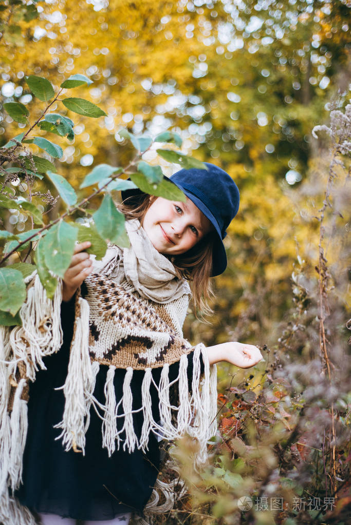 在秋天森林的披肩和帽子的女孩