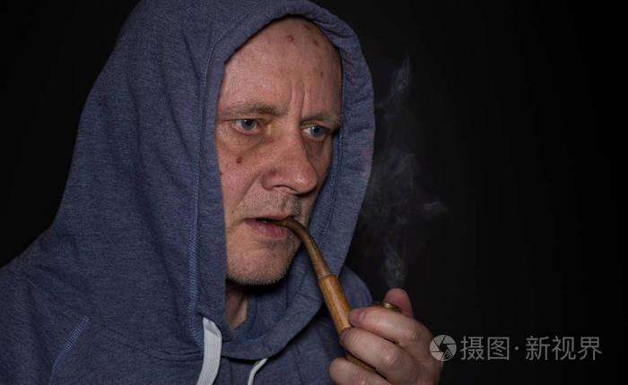 在黑暗中吸烟烟斗的成熟男子的漂亮肖像
