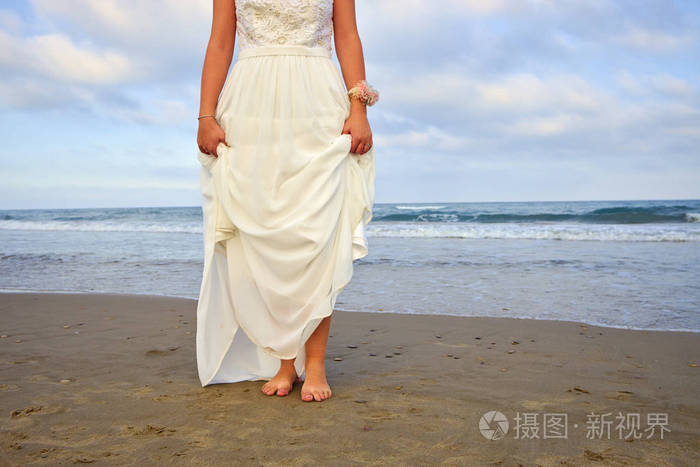 沙滩上赤脚结婚礼服的妇女