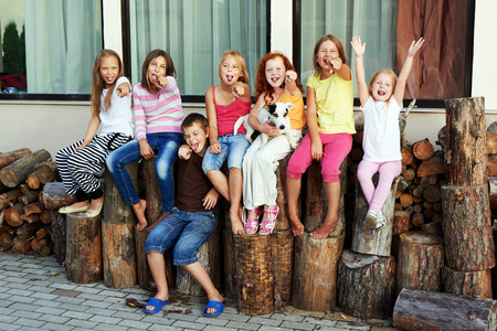 一群快乐的小朋友坐在后院的柴火上照片