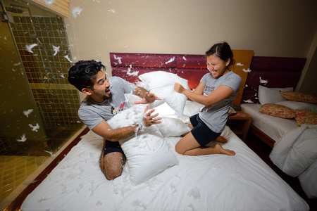 幸福恩爱的夫妻,有一个枕头在床上打架在晚上照片