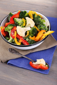 冷冻蔬菜在碗上餐巾，木桌背景
