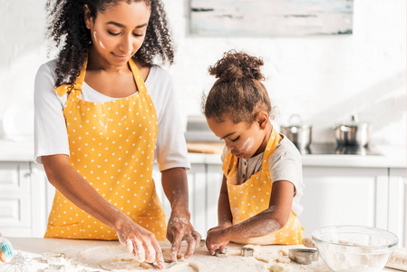非洲裔美国母亲和可爱的女儿准备饼干与模具在厨房