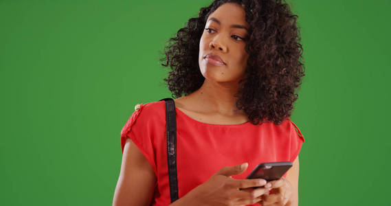 现代非洲裔美国女性在绿色屏幕上发短信时环顾四周