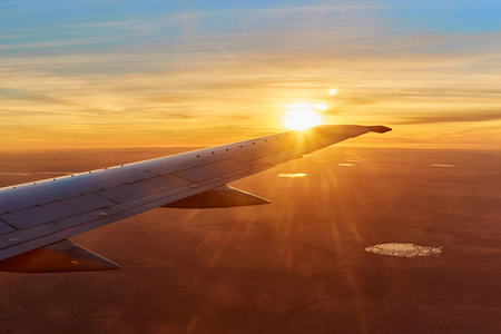 飞机翼飞行在日出与天空, 云彩在背景上。早晨日出与机翼的飞机。旅行概念