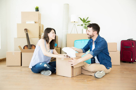 快乐的男人和女人在新公寓硬木地板上拆箱移动盒子