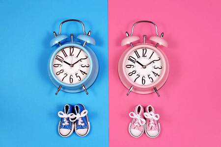 两个闹钟在蓝色粉红色背景, 男孩或女孩概念
