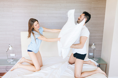幸福的夫妻有枕头战斗在酒店的房间里