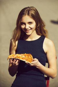 快乐的漂亮女孩微笑着美味的比萨片