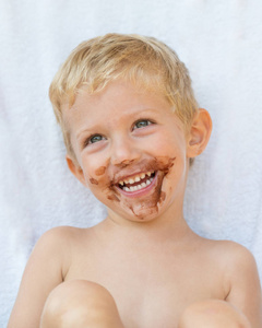 在白色背景上孤立的金发男孩与巧克力的肖像孤立, 男婴微笑