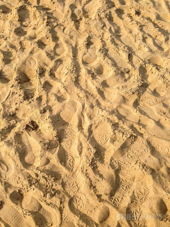 沙滩上的鞋子有脚印的沙子的质地阳光明媚的夏日