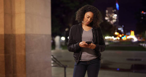 在城市环境中, 在外面的电话里不带微笑的现代黑人女性