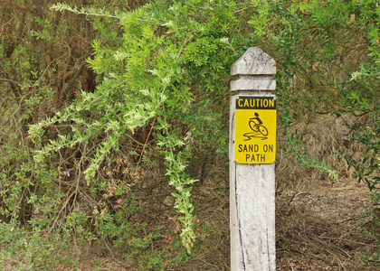黑色和黄色警告路径标志上的沙子