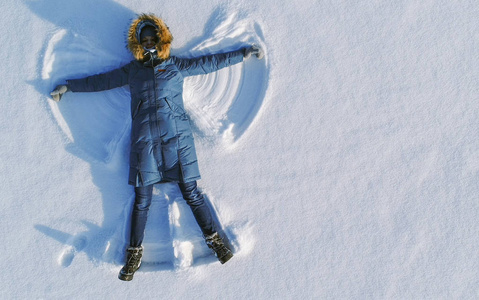 星际牛仔女人使雪天使躺在雪地里.顶部视图.空中飞行照片