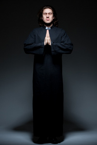 祈祷背景年轻牧师祈祷深色背景照片