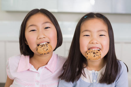 两种微笑享受饼干的年轻女孩的肖像