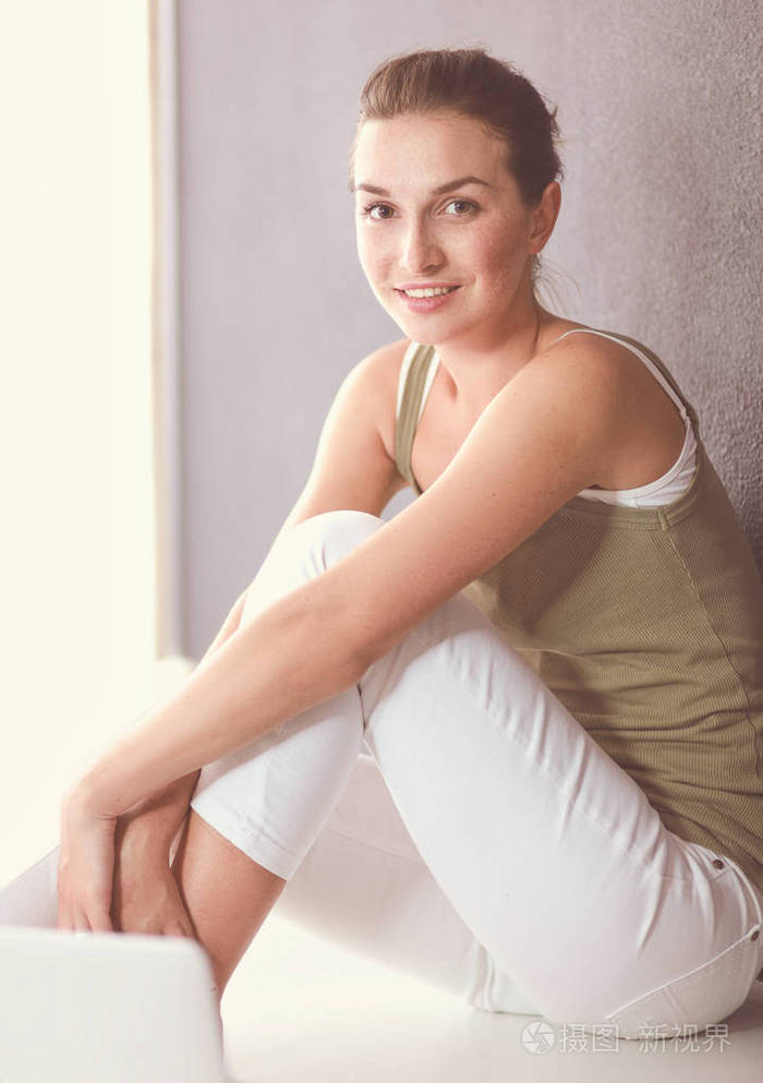 有魅力的白种人女孩坐在地上与杯壁附近的平板电脑