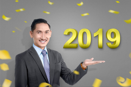 有吸引力的亚洲商人与开放手掌显示新年2019。新年快乐2019