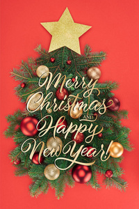 松树分枝, 金黄星和圣诞节球的顶部看法安排在圣诞树被隔绝的在红色与 快乐的圣诞节和愉快的新年 文字