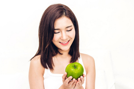 妇女持有和吃新鲜的绿色苹果在白色背景. 节食概念. 健康的生活方式