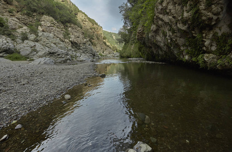 在撒丁岛腹地的典型全景中, 小鹅卵石海滩与山中的一条小溪融合在一起