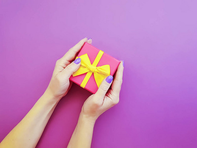 妇女的手拿着一个礼品盒上的彩色背景
