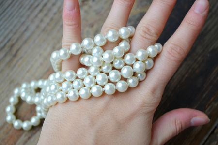 女人的手拿着一串珍珠项链照片