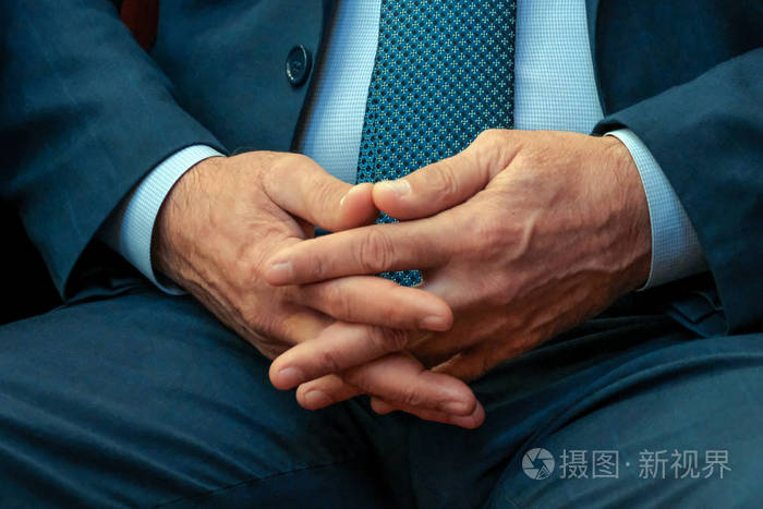 手指交叉在他们之间男性双手特写镜头抽象的中年男子在西装思想中的