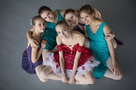 五个年轻的芭蕾舞演员坐在地板上，期待着 ca