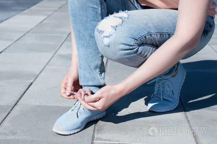 这个女孩在运动鞋上系鞋带特写