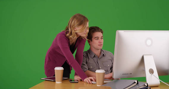 在绿色屏幕上工作的女性职业监督男性同事