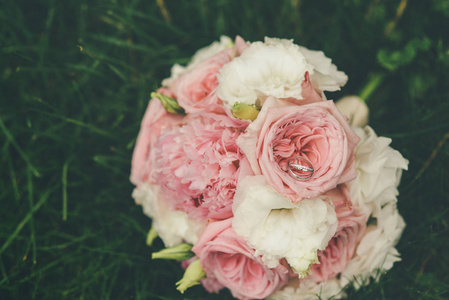 躺在草地上的粉红色和白色的玫瑰花的婚礼花束