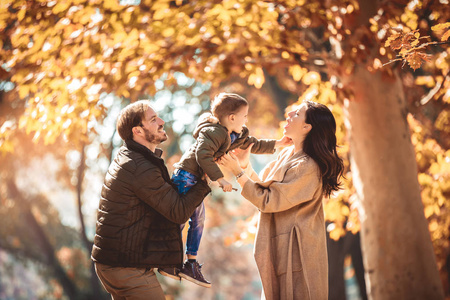 年轻的家庭有乐趣在秋季公园与他的儿子