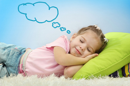 枕头小女孩可爱的小女孩上多彩的枕头睡觉和做梦在蓝色背景上照片