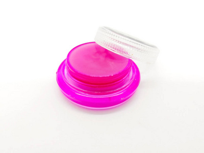 药物, 医疗和时尚概念。粉红色的唇膏在粉红色的小盒子和透明的盖子, 提高嘴唇的水分。在白色背景和复制空间上隔离