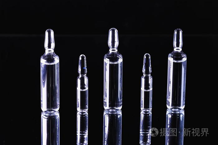 医疗准备.治疗疾病.黑色背景有有色液体的安瓿