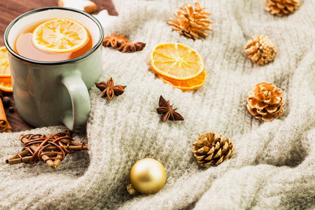 冬季和新年主题。圣诞茶与香料, 一杯茶与橙色, 肉桂, 八角, 在一个形状的星, 冷杉锥, 胡椒和灰色围巾在木制背景