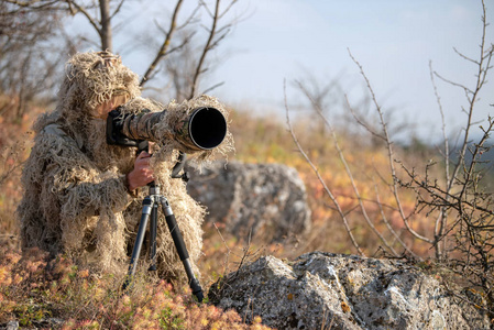 工作在野外穿着伪装服伪装野生动物摄影师照片