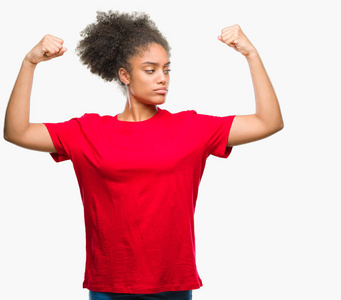 年轻的美国黑人妇女在孤立的背景下显示手臂肌肉微笑自豪。健身理念