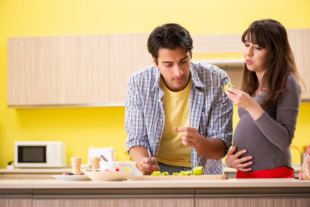 男子和孕妇在厨房里准备沙拉