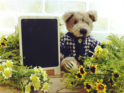 可爱的泰迪熊坐在木桌与人造花家庭装饰