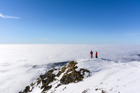 云层上方山顶上的两个滑雪者