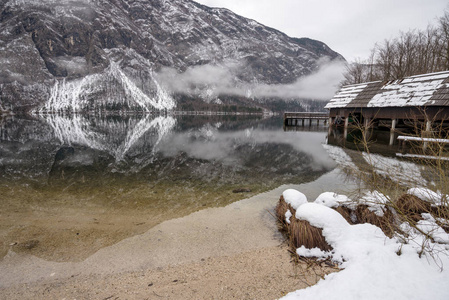 美丽的冬天湖 Bohinj 与木码头和山在背景反射在水中