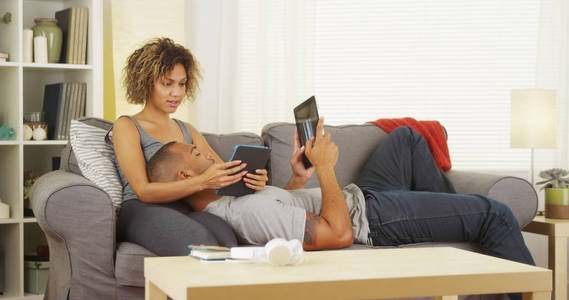 在沙发上使用平板电脑的黑人夫妇