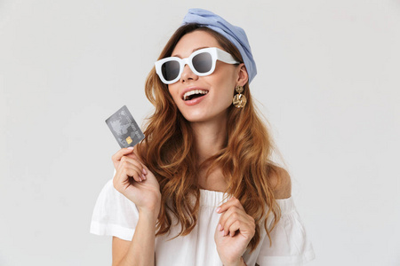 可爱的兴奋的女人的照片20s 戴墨镜微笑和持有信用卡隔离的白色背景