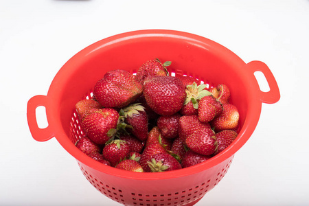 用红色塑料过滤器冲洗新鲜成熟的草莓