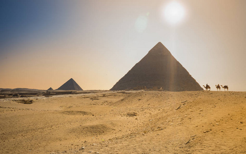 贝都因人骑骆驼在沙漠中的金字塔附近